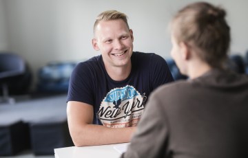 Henkilöt keskustelevat pöydän ääressä