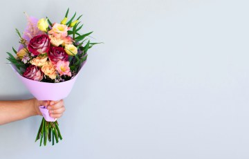 Käsi, joka ojentaa kukkakimppua