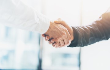 Kuvituskuva, jossa kaksi kättelevää kättä. 