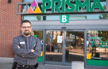 Valokuvassa on Prisman myymäläpäällikkö Anssi Vilen. Anssi seisoo Prisman edessä ja hymyilee. Hänellä on päällään Prisman työasu. 