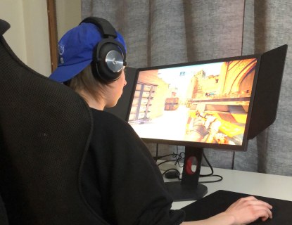 Hyrian esport-urheilija pelaa kotonaan tietokoneella työpöytänsä äärellä.