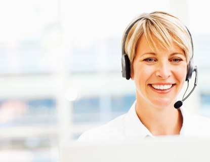 Asiakaspalveluhenkilö headset-päässään tietokoneen ruutu edessään