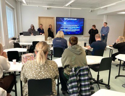 Opiskelijoita luokassa kuuntelemassa esitystä